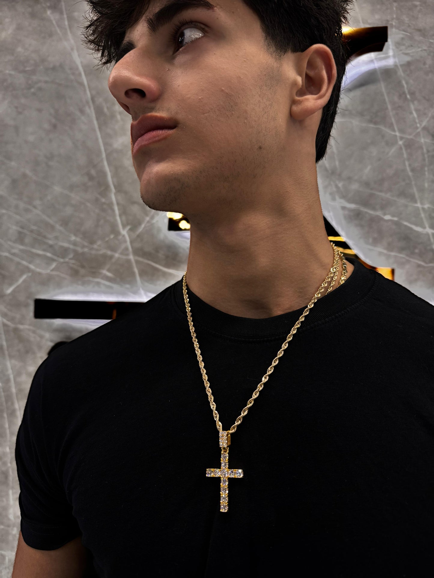 “Male model wearing a 14K gold cross pendant with 50-point round diamonds, styled over a clean T-shirt for a subtle, stylish expression of faith and luxury.”