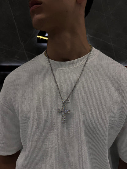 "Male model wearing a double-layered diamond cross pendant on a gold rope chain, styled over a black shirt — showcasing luxury streetwear with a bold, elegant aesthetic."